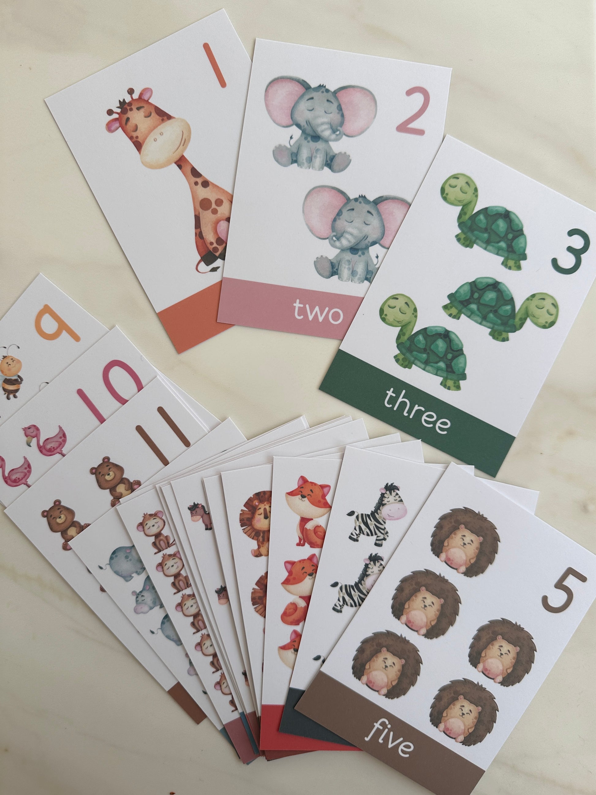 Educational cards with numbers and animal illustrations on a light surface
